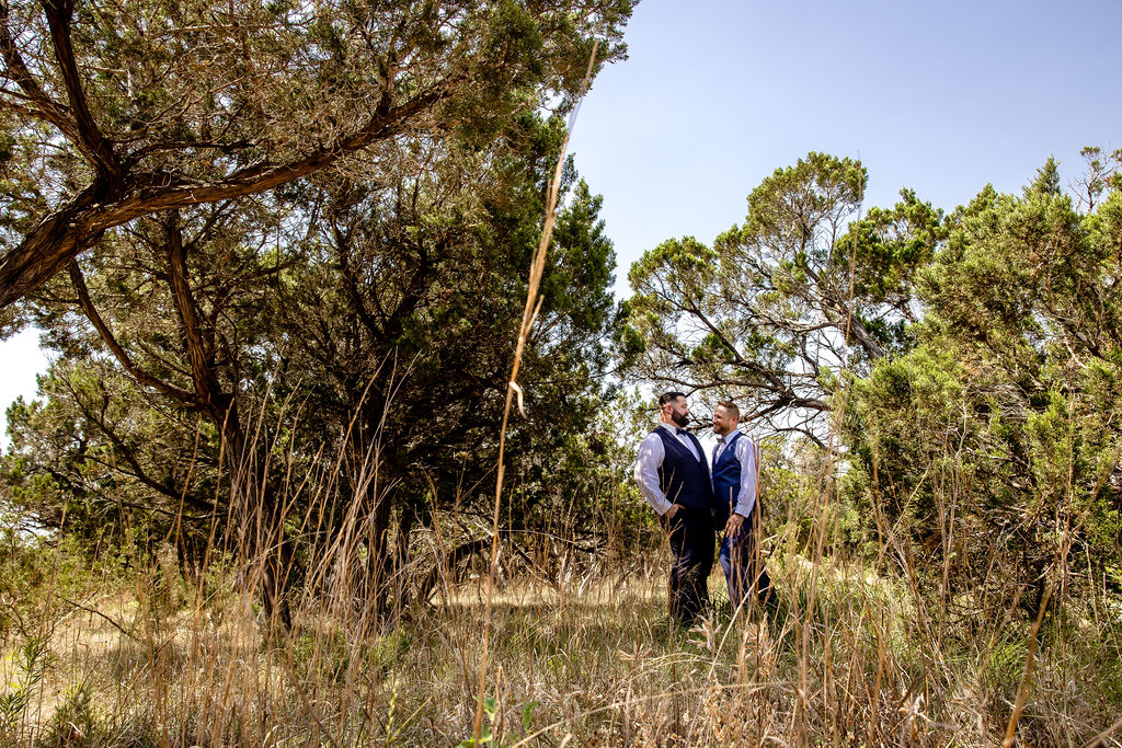 two grooms stand together in grass for their elopement photos