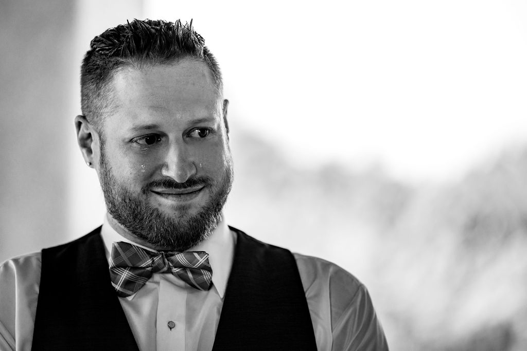 a groom cries at his wedding ceremony in a black and white photo